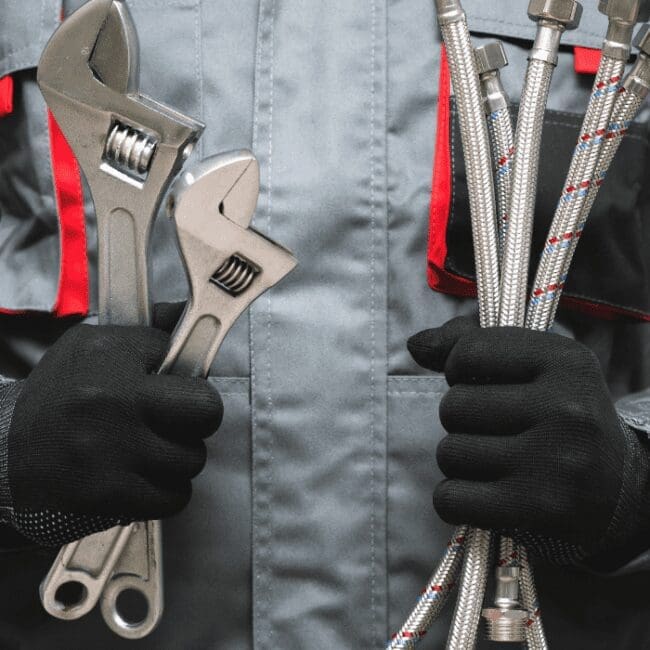 A Commercial Plumber is holding wrench and pipefitting tools