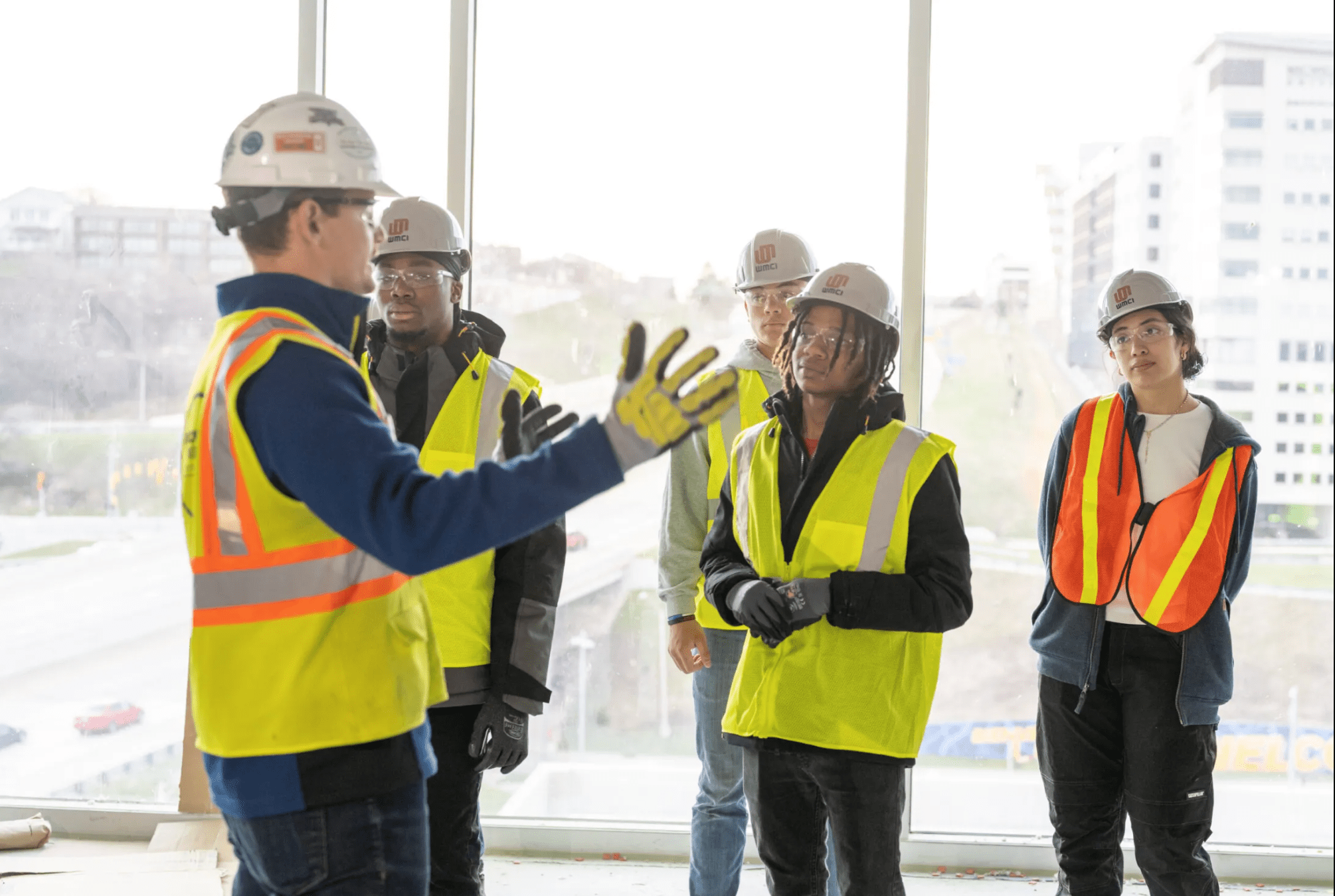 WMCI High School Program students listen to an instructor on one of their field trips to tour a Grand Rapids highrise construction job site.