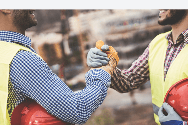 Two teammates grasp hands - supporting each other emotionally and psychologically on the jobsite.