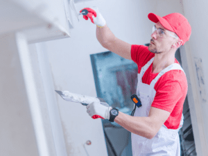 A drywalling installer works on a commercial construction project