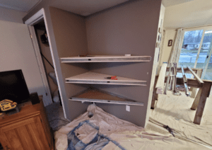 The first step in drywalling instructor Clark Causely's home project creating an alcove for his living room. Three shelves have been installed.